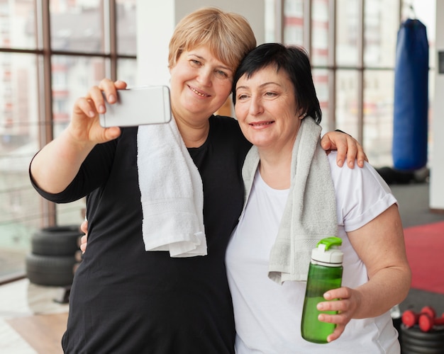 Foto gratuita mujeres mayores que toman selfie en el gimnasio