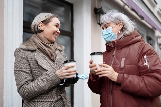 Mujeres mayores de tiro medio con tazas de café.