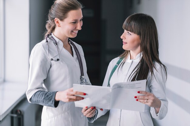 Mujeres medic alegre con papeles en clínica