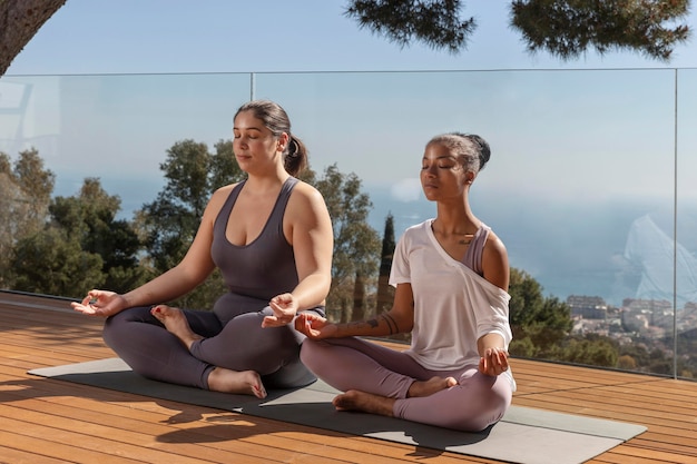 Foto gratuita mujeres meditando sobre estera de yoga