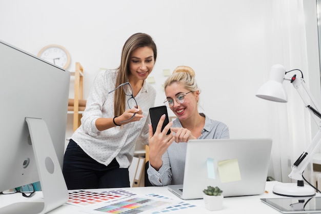 Mujeres mirando por teléfono en la oficina