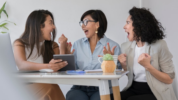 Mujeres modernas mirando algo divertido en la tableta