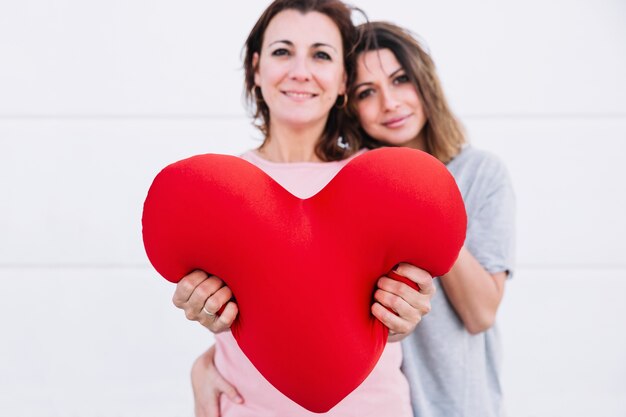 Mujeres mostrando corazón de felpa y mirando a la cámara