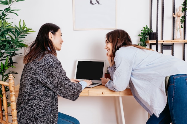 Mujeres multiétnicas alegres en la computadora portátil