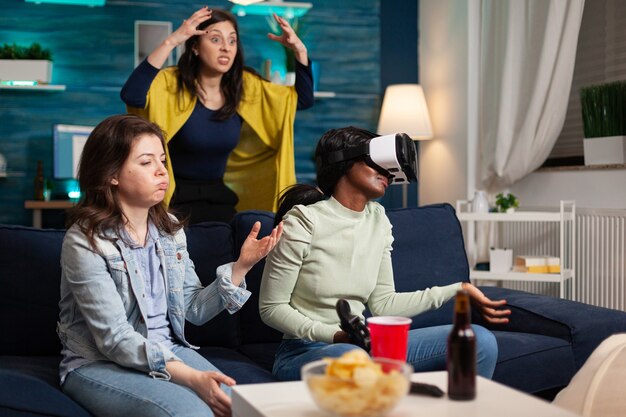 Mujeres multiétnicas molestas después de perder jugando videojuegos con gafas de realidad virtual