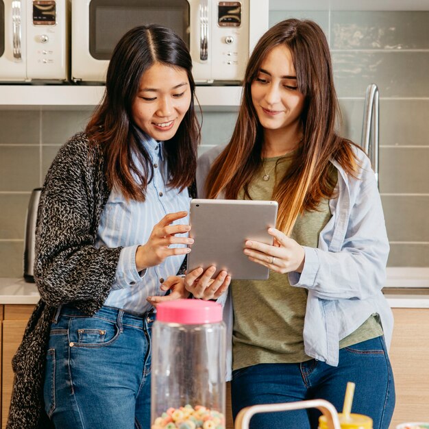 Mujeres multiétnicas con tableta en la cocina