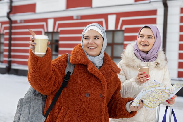 Mujeres musulmanas con hijabs tomando café y consultando un mapa para explorar la ciudad mientras están de vacaciones