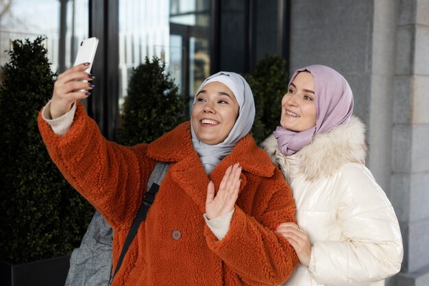 Mujeres musulmanas con hijabs tomándose una selfie y saludando mientras están de vacaciones