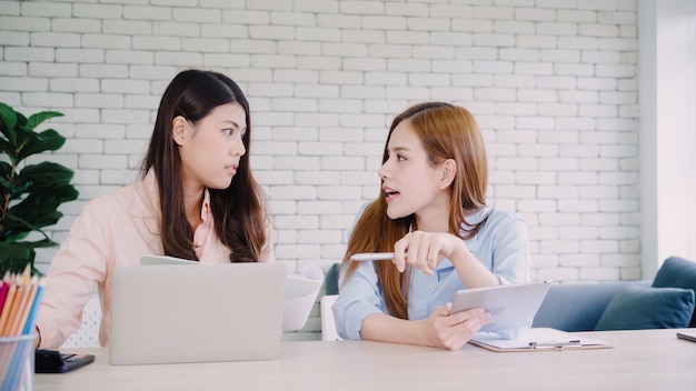 Mujeres de negocios asiáticas creativas inteligentes atractivas en la ropa de sport elegante que trabaja en el ordenador portátil mientras que se sienta