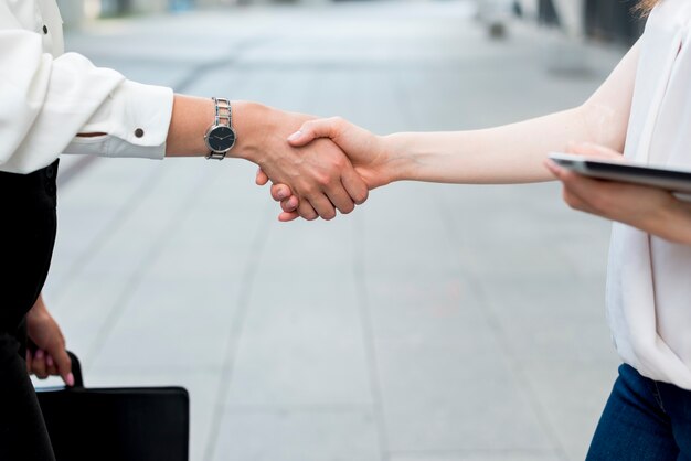 Mujeres de negocios dándose la mano en la calle