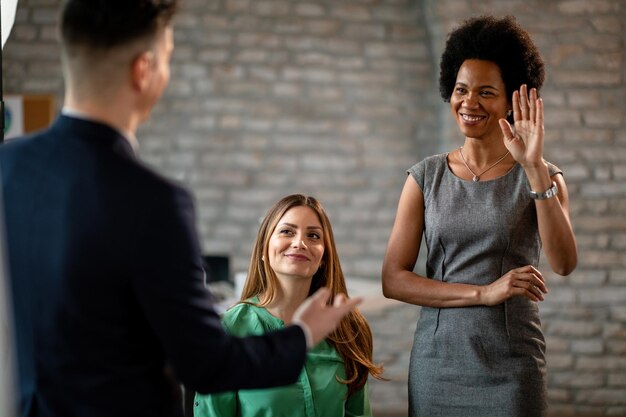 Mujeres de negocios felices que asisten a un seminario en la oficina El foco está en una mujer de negocios negra levantando la mano para hacer la pregunta