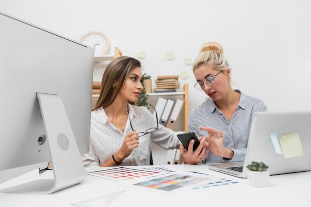 Mujeres de negocios que buscan en el teléfono