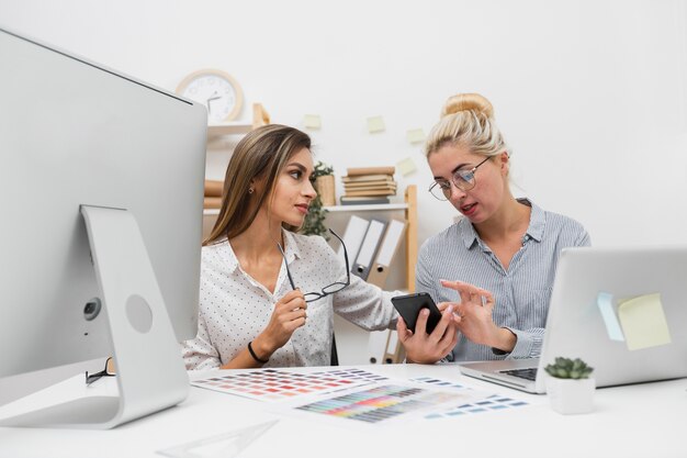 Mujeres de negocios que buscan en el teléfono