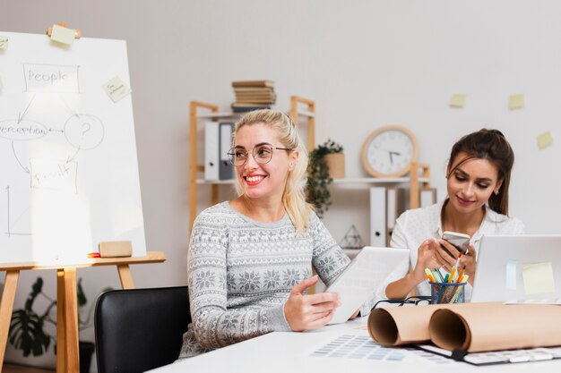 Mujeres de negocios sonrientes que se sientan en la oficina