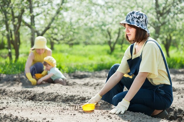 las mujeres con niños trabajan en el jardín de verduras