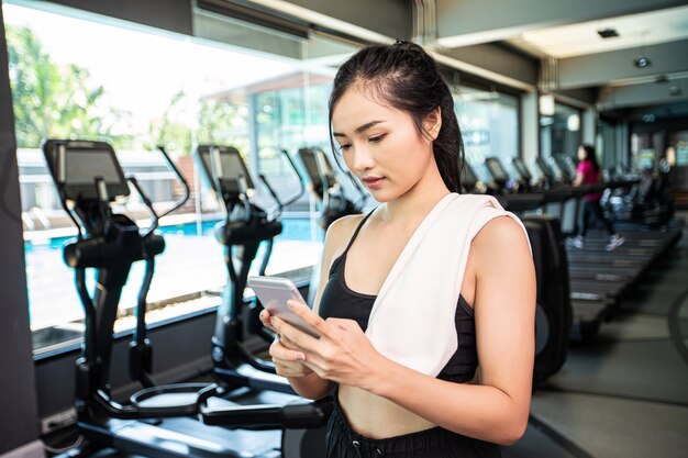 Mujeres de pie jugando alegremente el teléfono en el gimnasio.