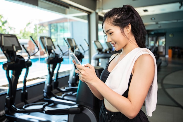 Mujeres de pie jugando alegremente el teléfono en el gimnasio.