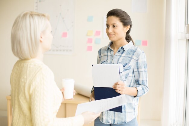 Mujeres de pie en la sala de oficina hablando