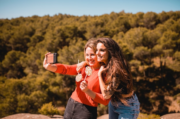 Mujeres con piruletas tomando selfie en naturaleza