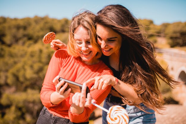 Mujeres con piruletas usando teléfono inteligente