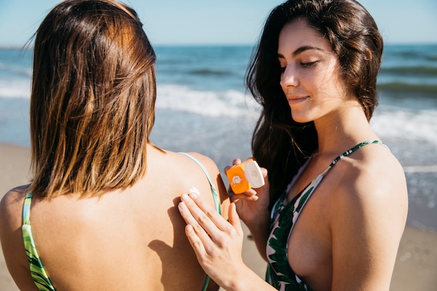 Mujeres en la playa con crema solar
