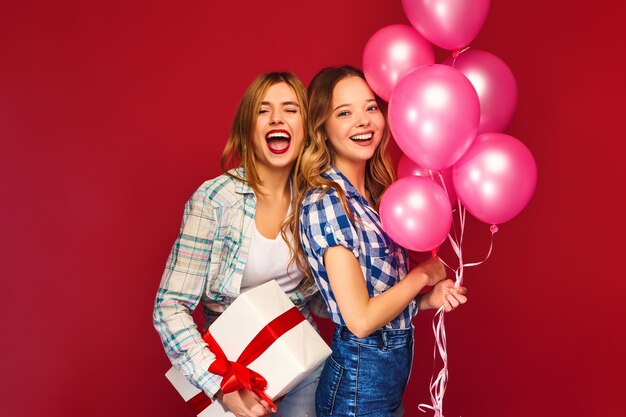 Mujeres posando con una gran caja de regalo y globos rosas