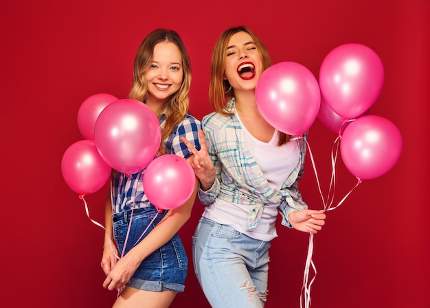 Mujeres posando con una gran caja de regalo y globos rosas