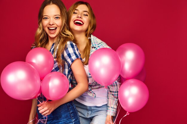 Mujeres posando con una gran caja de regalo y globos rosas