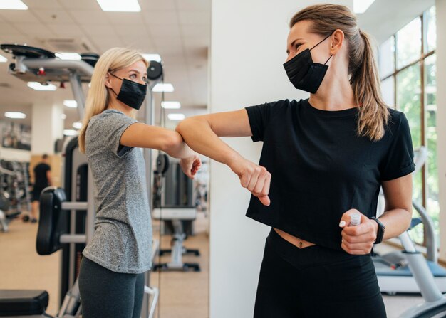 Mujeres practicando el saludo del codo en el gimnasio durante la pandemia