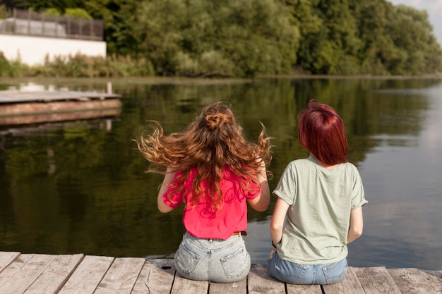 Foto gratuita las mujeres que se quedan en el muelle mirando el lago