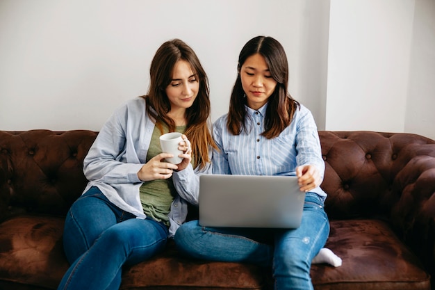 Mujeres que usan la computadora portátil en el sofá