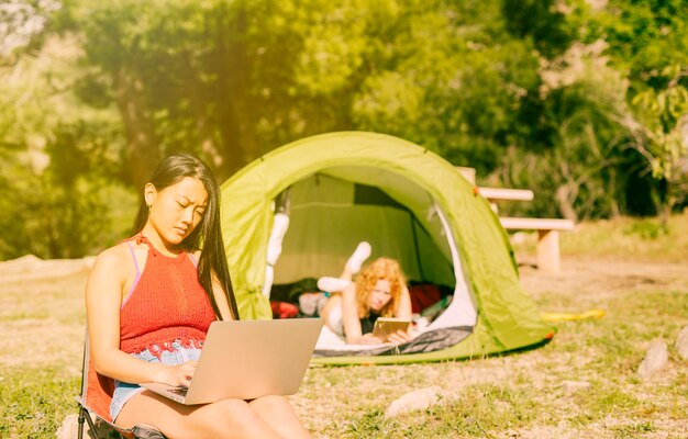 Mujeres que usan gadgets mientras acampan.