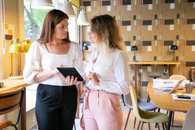 Mujeres reflexivas de pie en el interior y mirándose