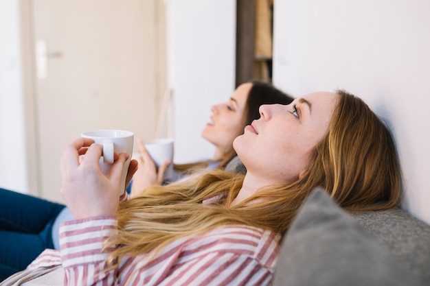 Foto gratuita mujeres relajadas con tazas mirando hacia arriba