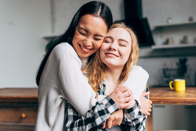 Mujeres riendo abrazando en casa