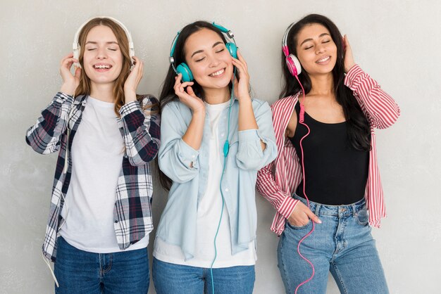 Mujeres riendo de pie y escuchando música en auriculares de colores