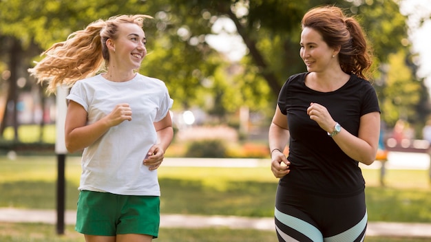 Mujeres en ropa deportiva corriendo juntas en el parque.