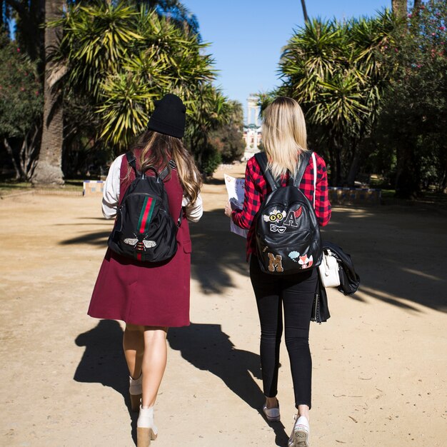 Mujeres sin rostro con mapa caminando en el parque