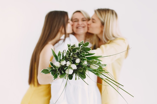 Mujeres rubias alegres de dos generaciones aisladas sobre fondo blanco. Ramo de flores.