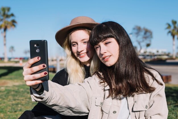 Mujeres seguras de moda tomando selfie en sol