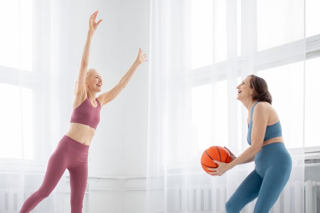 Mujeres senior de tiro medio entrenando con pelota