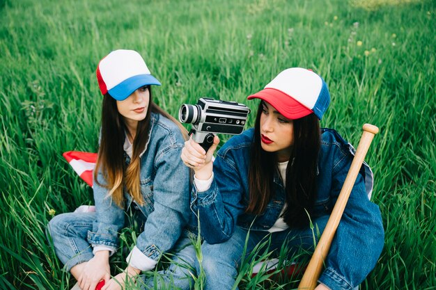 Mujeres sentadas en el campo con ropa casual y gorras de colores