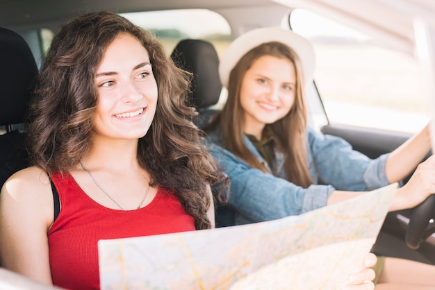 Foto gratuita mujeres sentadas en el coche con el mapa