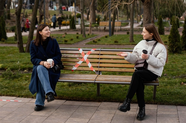 Mujeres sentadas a distancia y con máscara