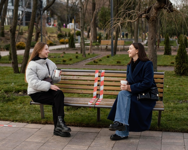 Mujeres sentadas a distancia y con máscara