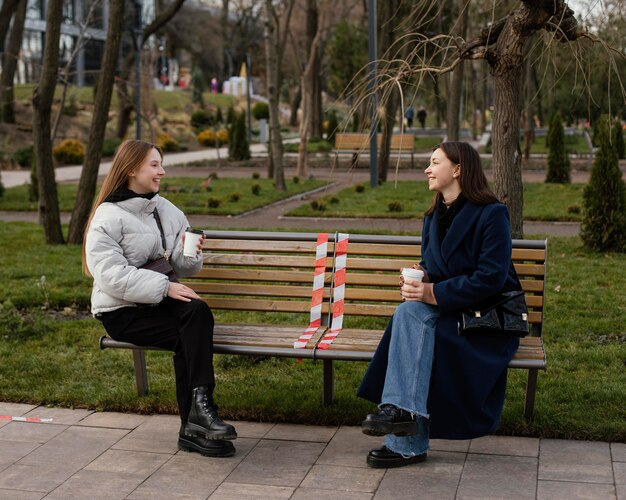 Mujeres sentadas a distancia y con máscara