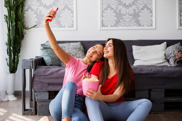 Mujeres sentadas en el piso y tomando selfie