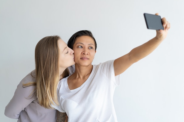 Mujeres serias besándose y tomando fotos selfie