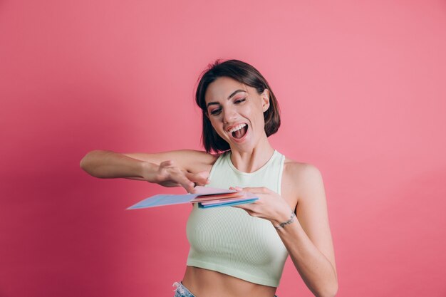 Mujeres sobre fondo rosa bastante divertidas tirando letras en el aire