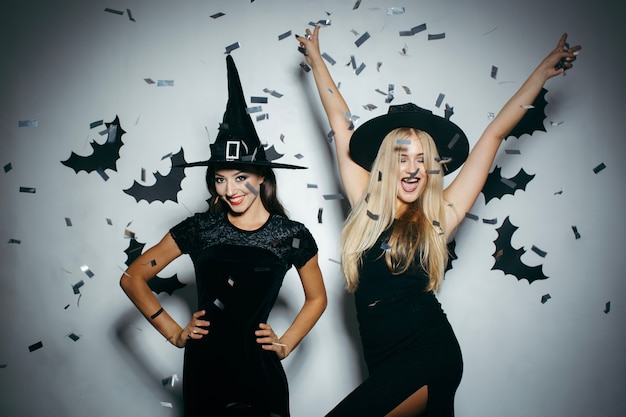 Foto gratuita mujeres en sombreros de halloween en confeti